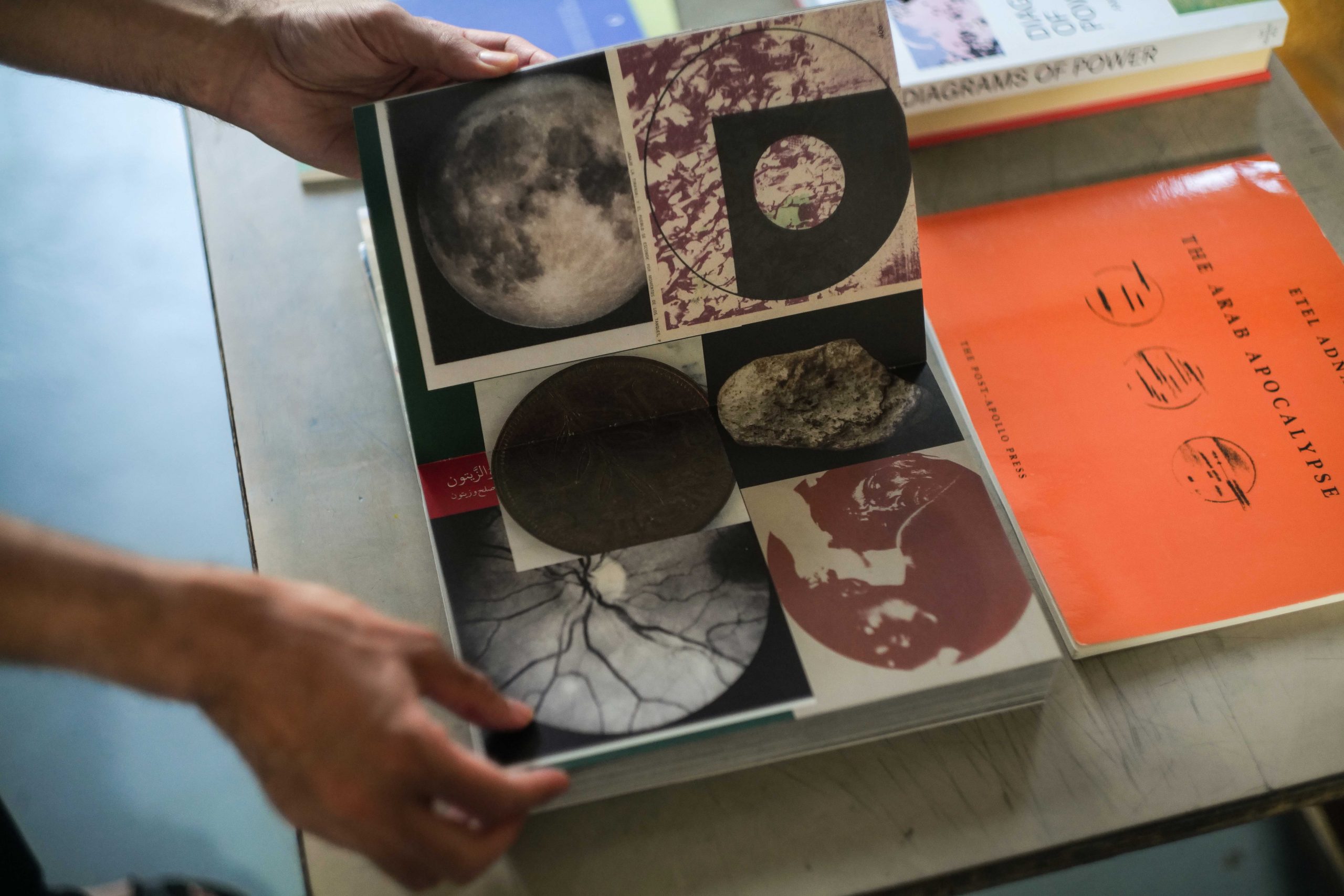 Two hands hold a book open showing images of planetary shapes.